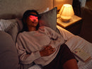 Halo light therapy glasses glowing red while a woman relaxes in bed